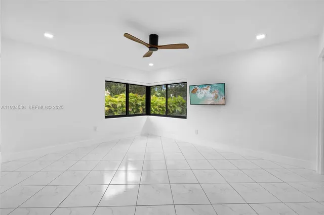 an empty room with windows and ceiling fan