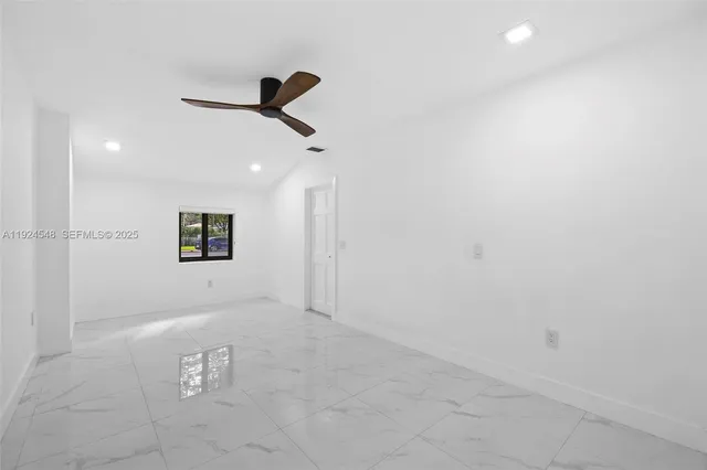 an empty room with a ceiling fan and window
