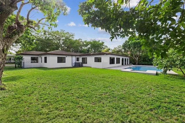 a backyard of a house with plants and large tree