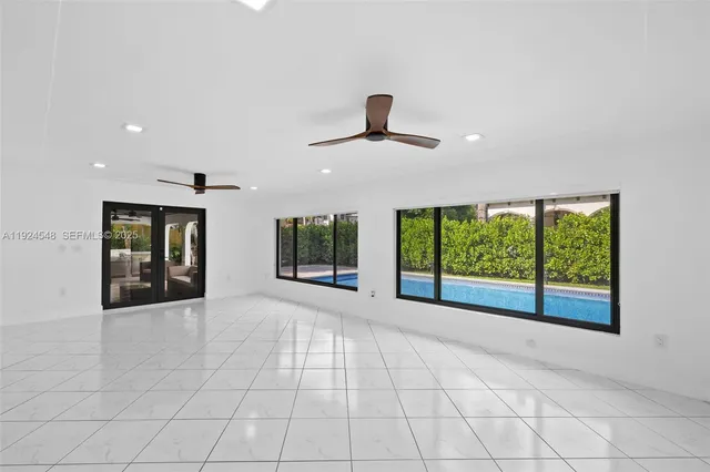 a view of an empty room with a window and a kitchen