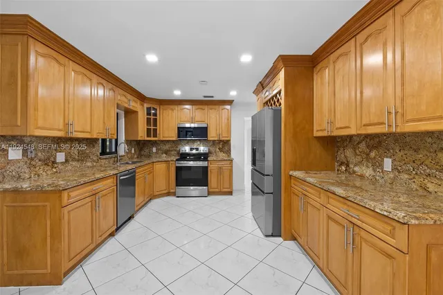 a kitchen with stainless steel appliances granite countertop a stove a sink and a refrigerator