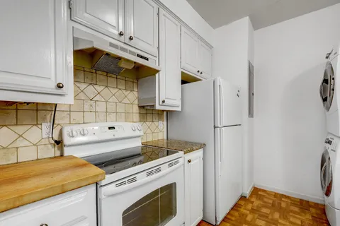 a kitchen with stainless steel appliances white cabinets and a stove top oven