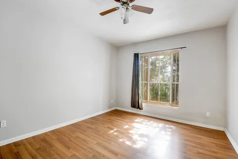 an empty room with a window and ceiling fan