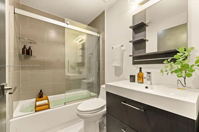 a bathroom with a sink a toilet a mirror a bathtub and shower