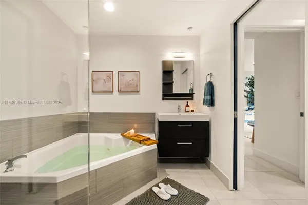 a bathroom with a tub a sink and a large mirror