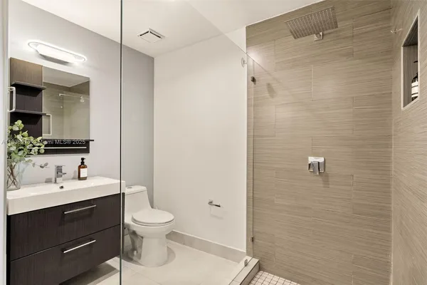 a bathroom with a toilet a sink a mirror a shower and vanity