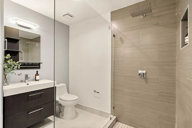 a bathroom with a toilet a sink a mirror a shower and vanity