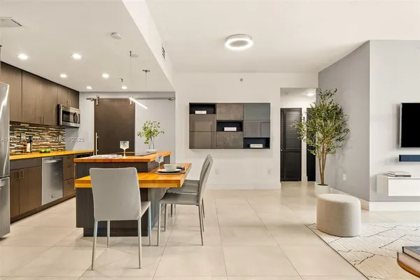 a kitchen with kitchen island stainless steel appliances a stove a sink a microwave a refrigerator and chairs