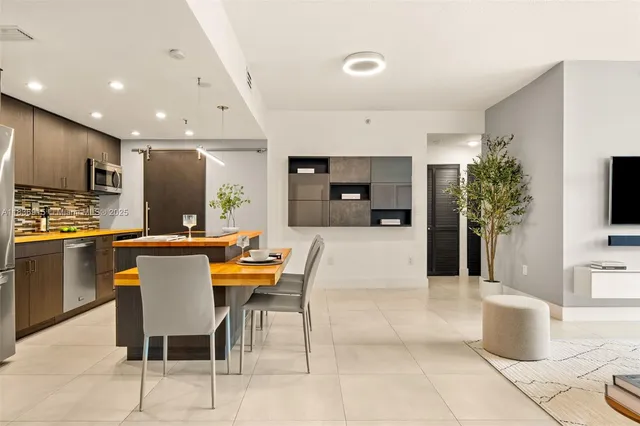 a kitchen with kitchen island stainless steel appliances a stove a sink a microwave a refrigerator and chairs