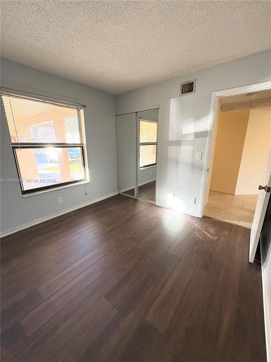 21904 Lake Forest Circle, Unit 203 Boca Raton, FL 33433 - Photo 4 of 11 an empty room with wooden floor and windows