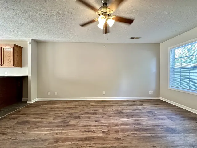 a view of an empty room with window and chandelier fan