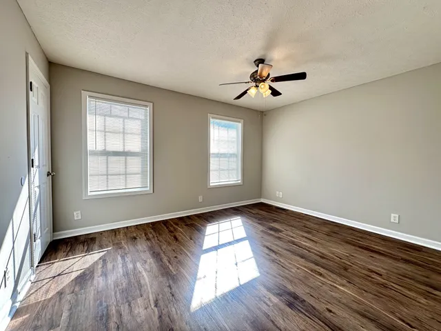 a view of empty room with wooden floor and fan
