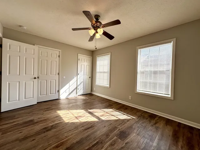 a view of empty room with wooden floor and fan