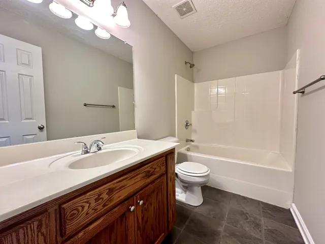 a bathroom with a sink a toilet a mirror a bathtub and shower