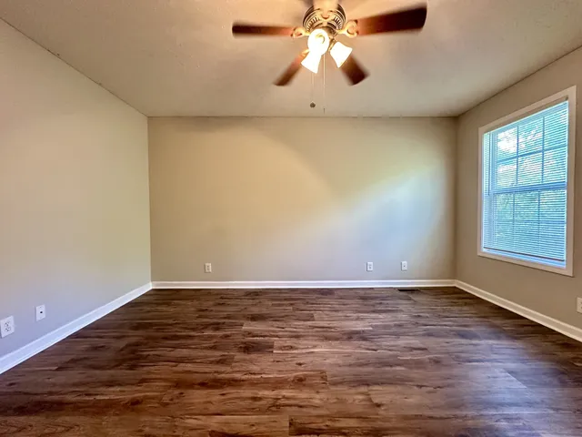 a view of an empty room with window and wooden floor