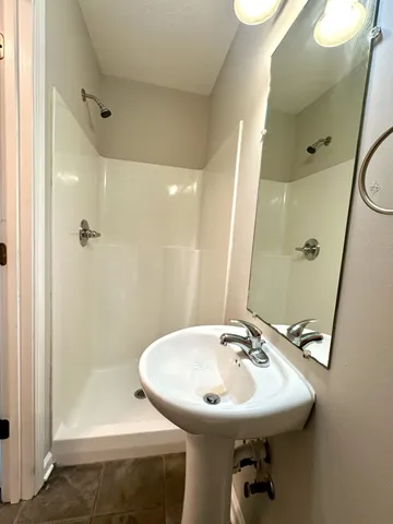 a bathroom with a sink shower and a mirror