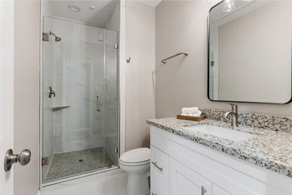 a bathroom with a granite countertop sink a toilet and shower