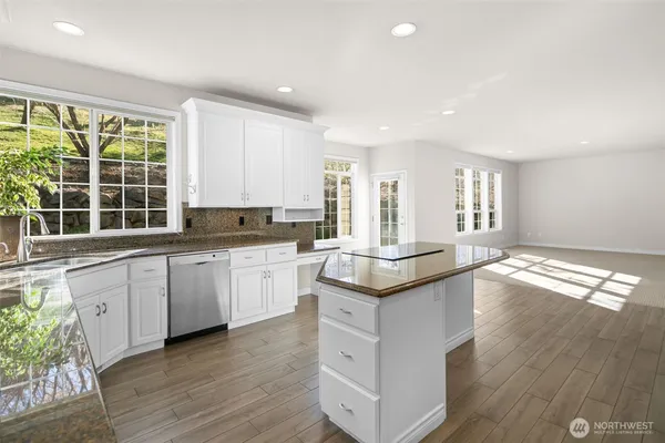 a kitchen with granite countertop white cabinets and wooden floor