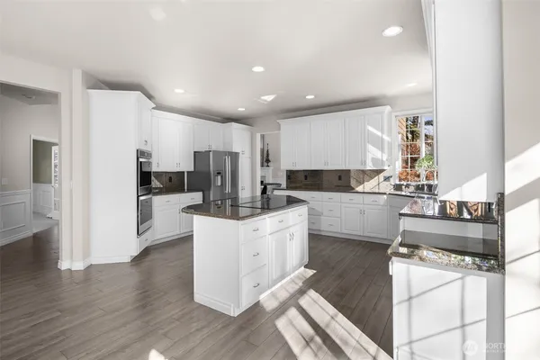 a kitchen with stainless steel appliances kitchen island granite countertop a refrigerator and a stove top oven