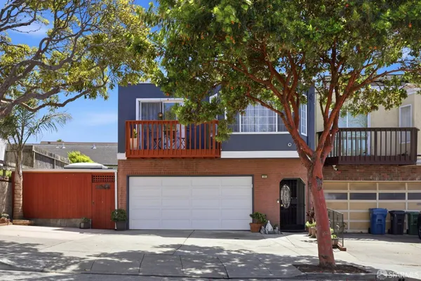 a front view of a house with a tree