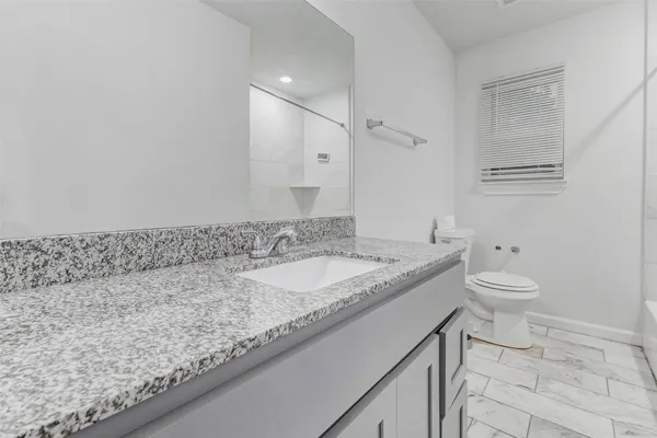 a bathroom with a granite countertop sink and a toilet