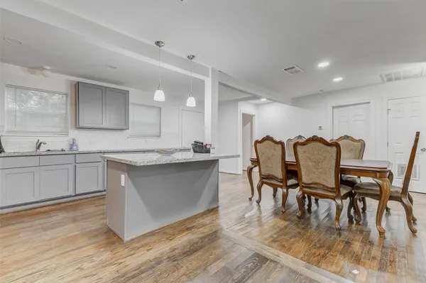 a kitchen with stainless steel appliances granite countertop a table chairs sink and cabinets