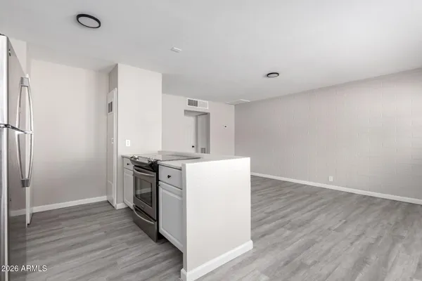 a kitchen with wooden floor and electronic appliances