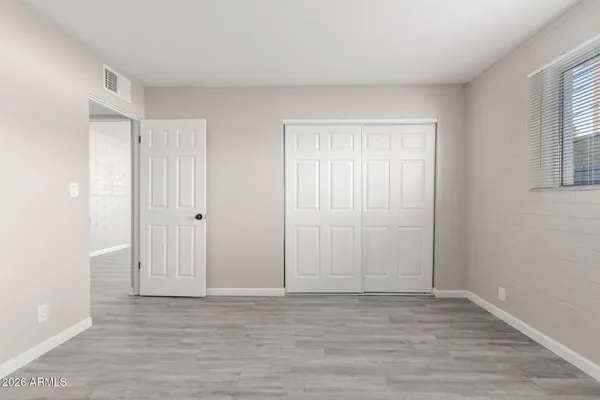 a view of an empty room with wooden floor and window