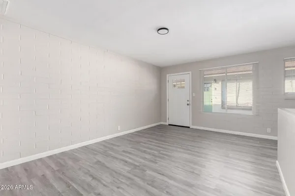 a view of an empty room with wooden floor and a window