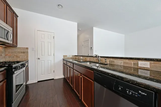 a kitchen with granite countertop stainless steel appliances a sink stove and cabinets