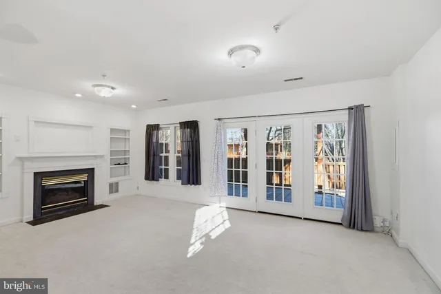 an empty room with windows and fireplace