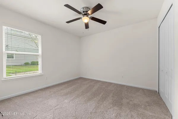 an empty room with a window and a fan