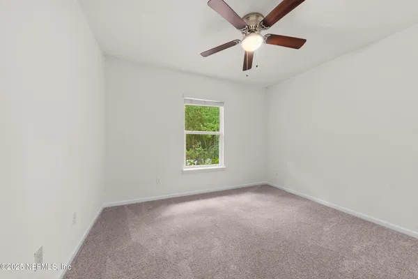 an empty room with a window and a fan