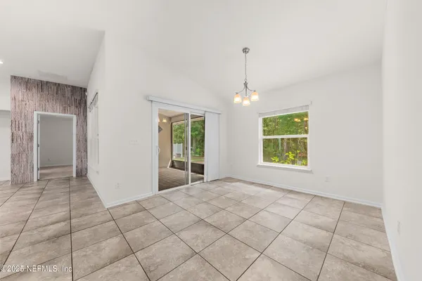 a view of an empty room with window and chandelier