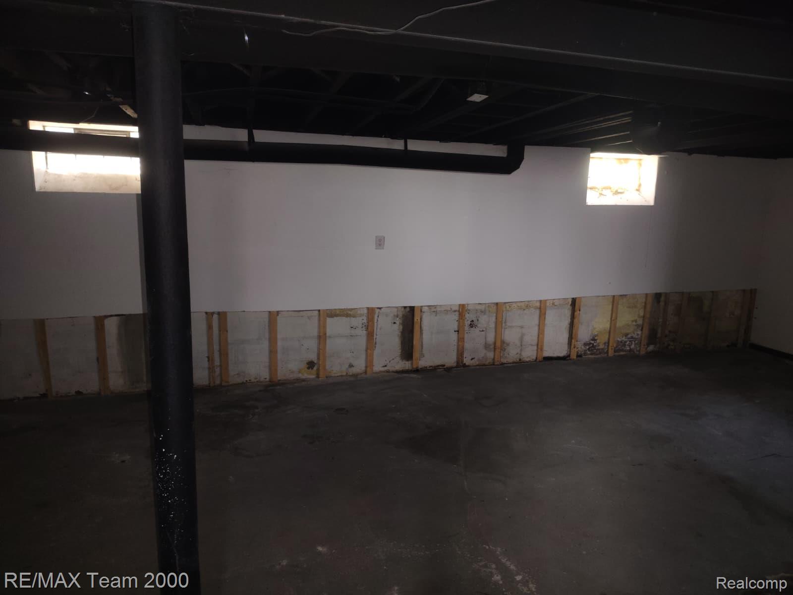 8860 Appoline Street Detroit, MI 48228 - Photo 31 of 45 Expansive unfinished lower level featuring two windows, exposed ceiling joists, white painted walls, and a concrete floor