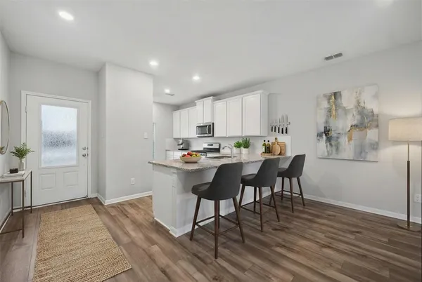 a kitchen with a dining table chairs and wooden floor