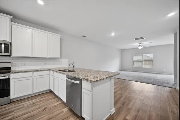 a kitchen with granite countertop cabinets stainless steel appliances a sink and wooden floor