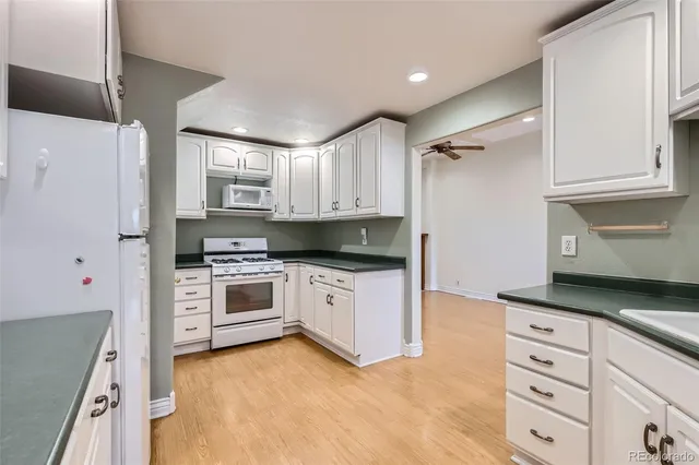 a kitchen with granite countertop white cabinets and white appliances