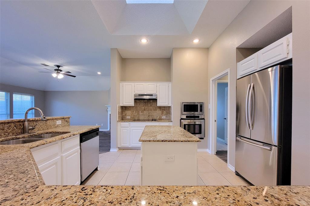 1604 Knoll Ridge Circle Corinth, TX 76210 - Photo 14 of 37 Kitchen featuring granite countertops, white cabinetry, a central island, stainless steel appliances, and tile flooring