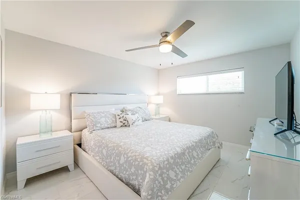 a bedroom with a bed and a flat tv screen on dresser