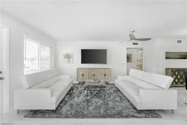a living room with furniture a flat screen tv and a window