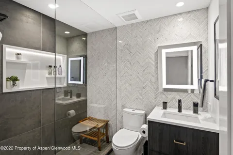 a bathroom with a toilet sink vanity and mirror