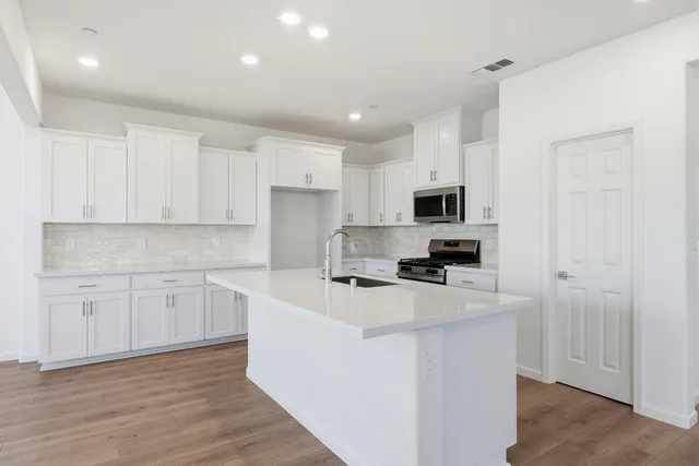 a kitchen with cabinets stainless steel appliances and wooden floor