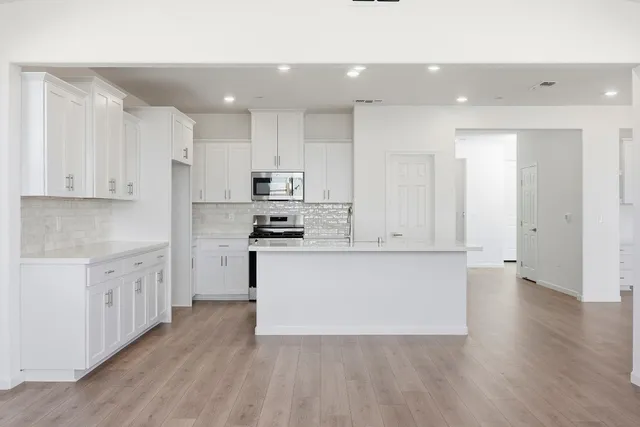 a kitchen with white cabinets and stainless steel appliances