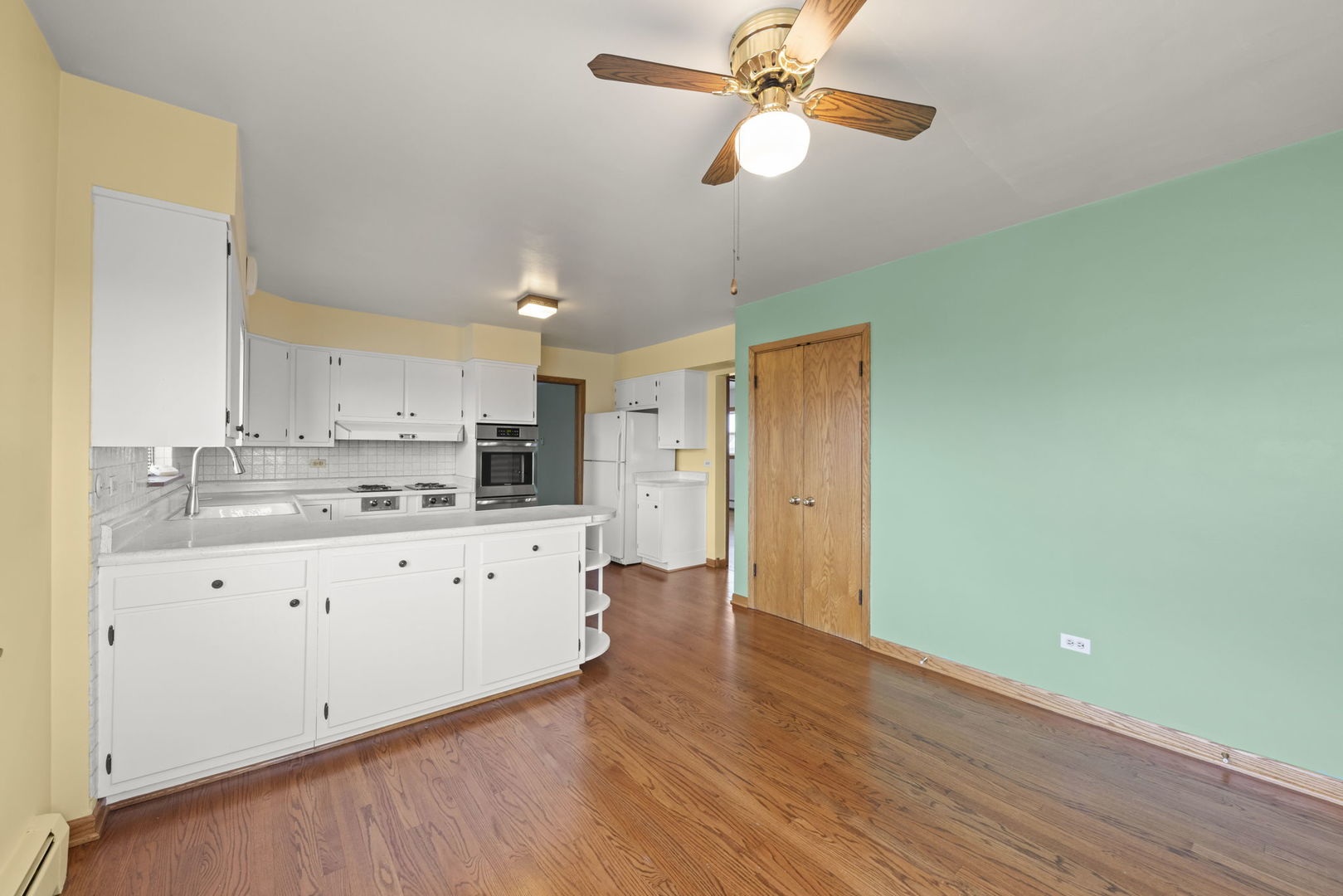 6401 West 52nd Street, Unit 2 Chicago, IL 60638 - Photo 6 of 18 a kitchen with granite countertop a stove a sink and white cabinets with wooden floor