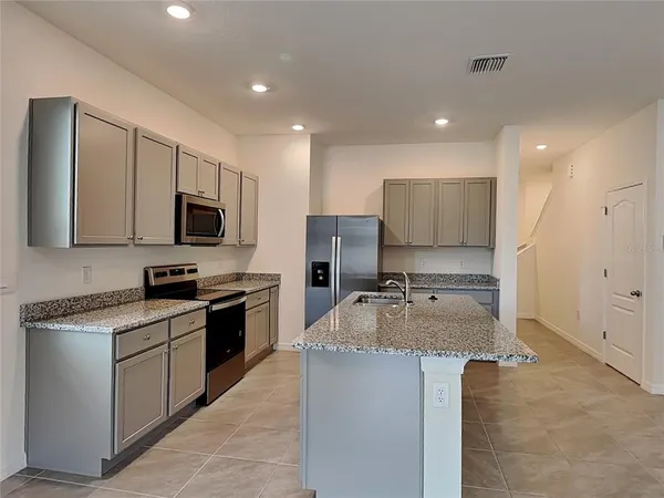 a kitchen with stainless steel appliances granite countertop a sink stove microwave and refrigerator