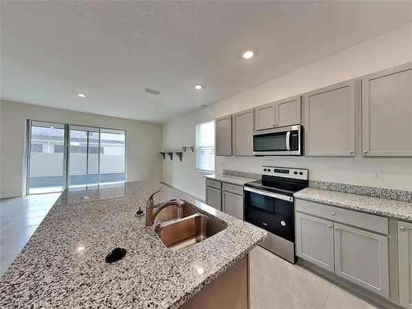 a kitchen with stainless steel appliances granite countertop a sink stove refrigerator and microwave
