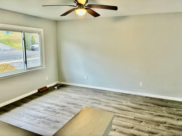 an empty room with wooden floor and windows