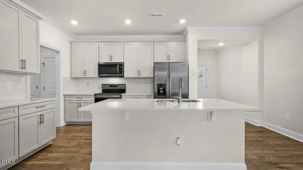 a kitchen with kitchen island a white counter top space stainless steel appliances and cabinets