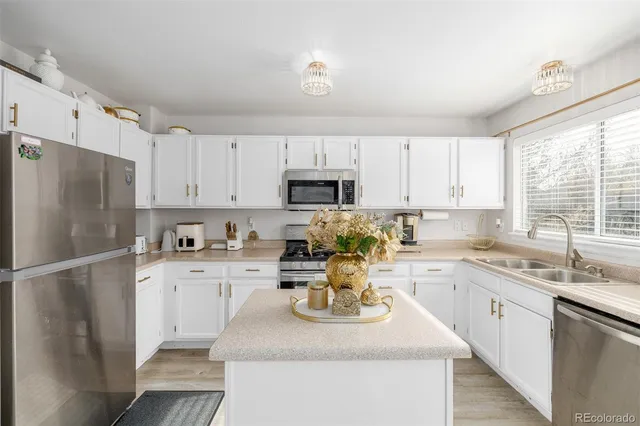 a kitchen with a sink a stove a refrigerator and white cabinets